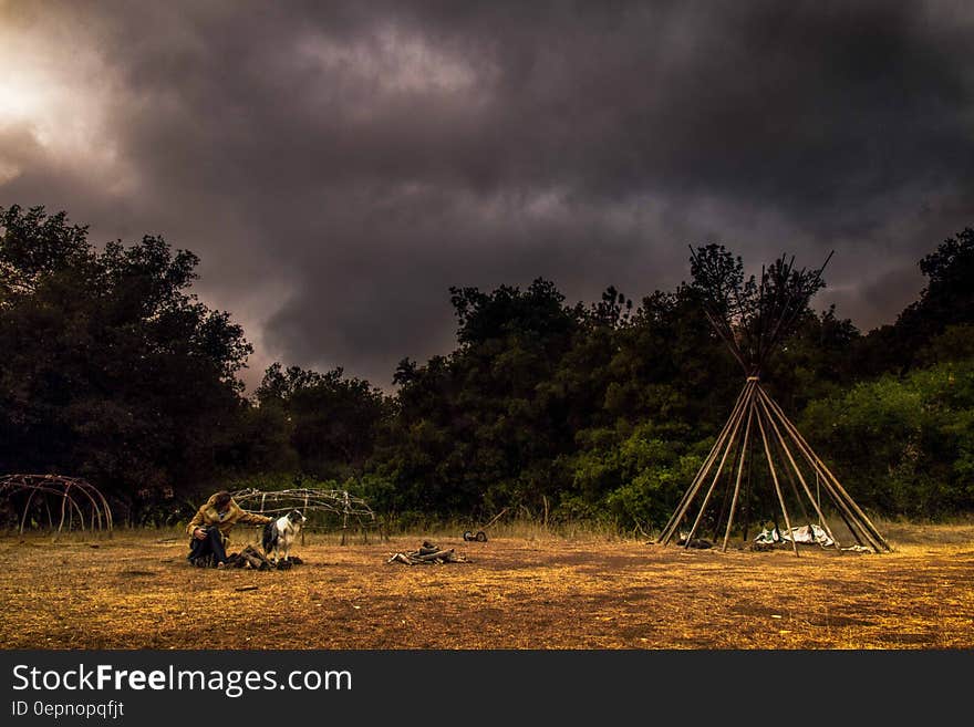 Camper in field under stormy skies.