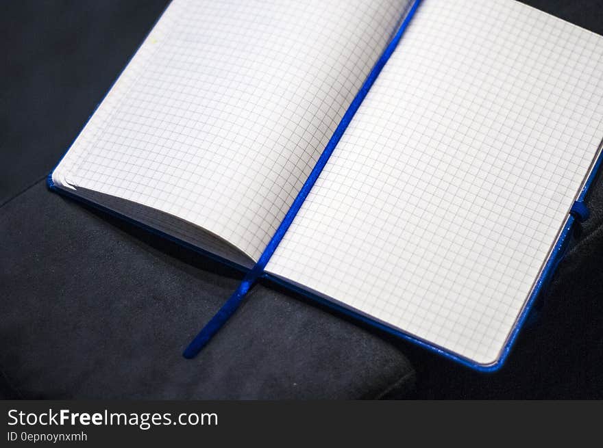 Blank open square ruled notebook lying on dark surface.