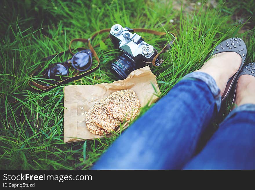 Girl resting on green grass with cookies and camera