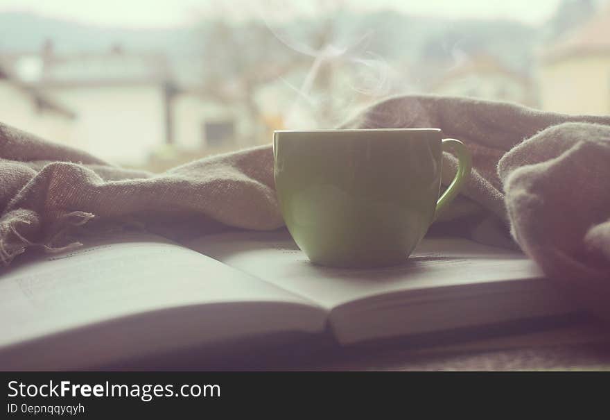 White Hot Mug on Book Near Linen