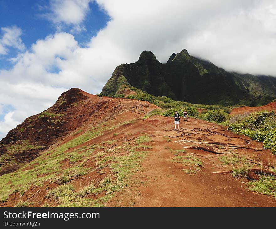 Hikers walking on red hills leading up to mountains. Hikers walking on red hills leading up to mountains.