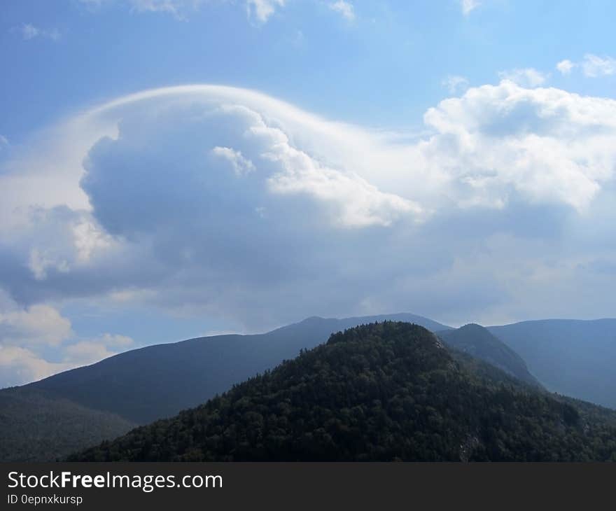 A cloud formation on blue skies over a mountain range. A cloud formation on blue skies over a mountain range.