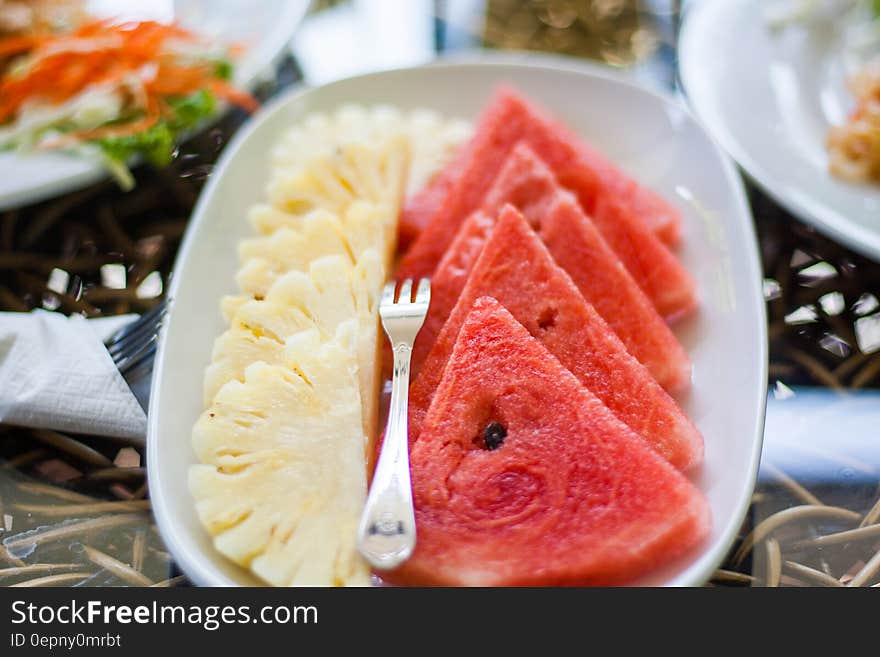 Sliced Watermelon and Pineapple Fruit With Stainless Steel Fork Placed on White Ceramic Rectangular Plate