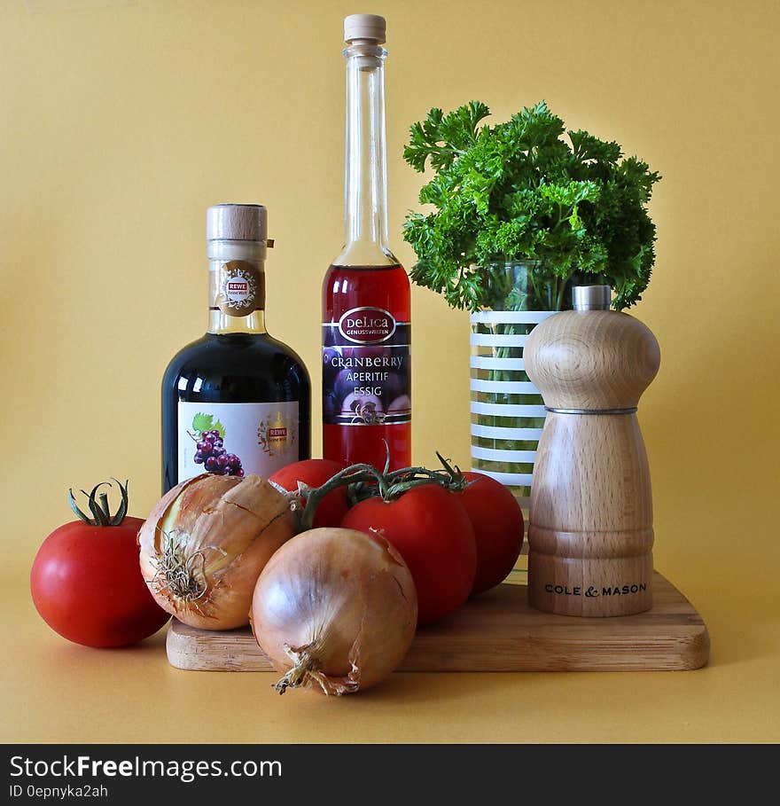 Fresh tomatoes, onions and herbs on cutting board with vinegar and condiments, studio background. Fresh tomatoes, onions and herbs on cutting board with vinegar and condiments, studio background.