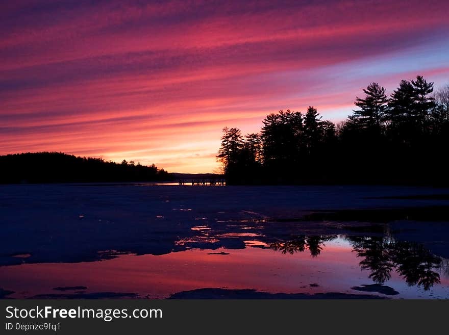 A view of a still lake at sunset.