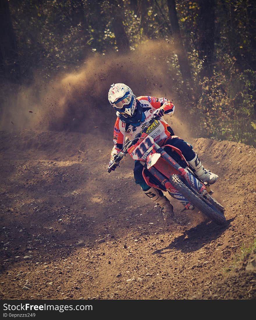 Man in White and Orange Motocross Overall Riding His Motocross Dirt Bike during Daytime