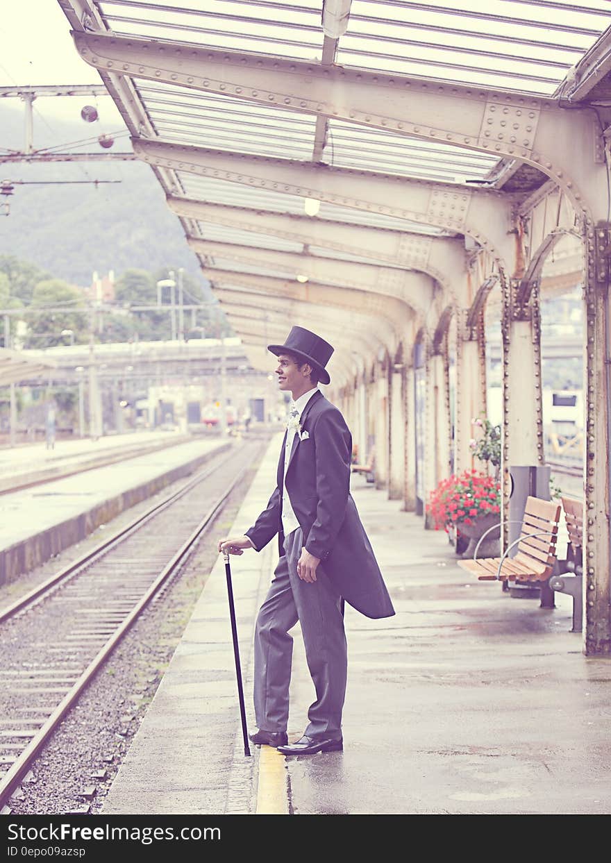 Sepia Effects Photo of Man in Black Tuxedo Standing on Train Station during Daytime