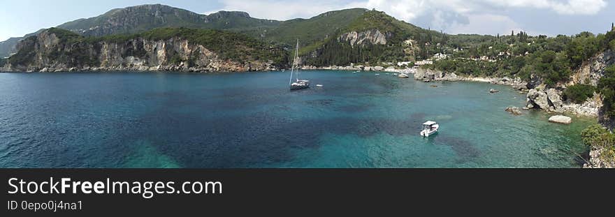 Boats on Ocean Near Gray and Green Mountains during Daytime