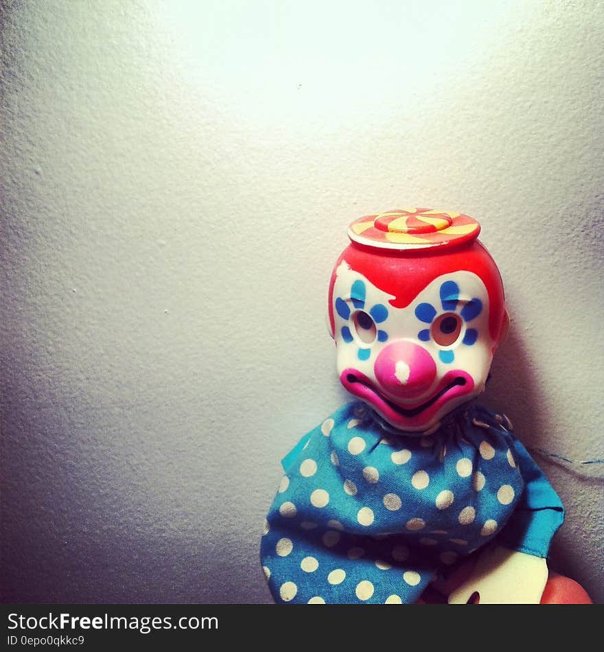 Close up of clown doll against white wall.