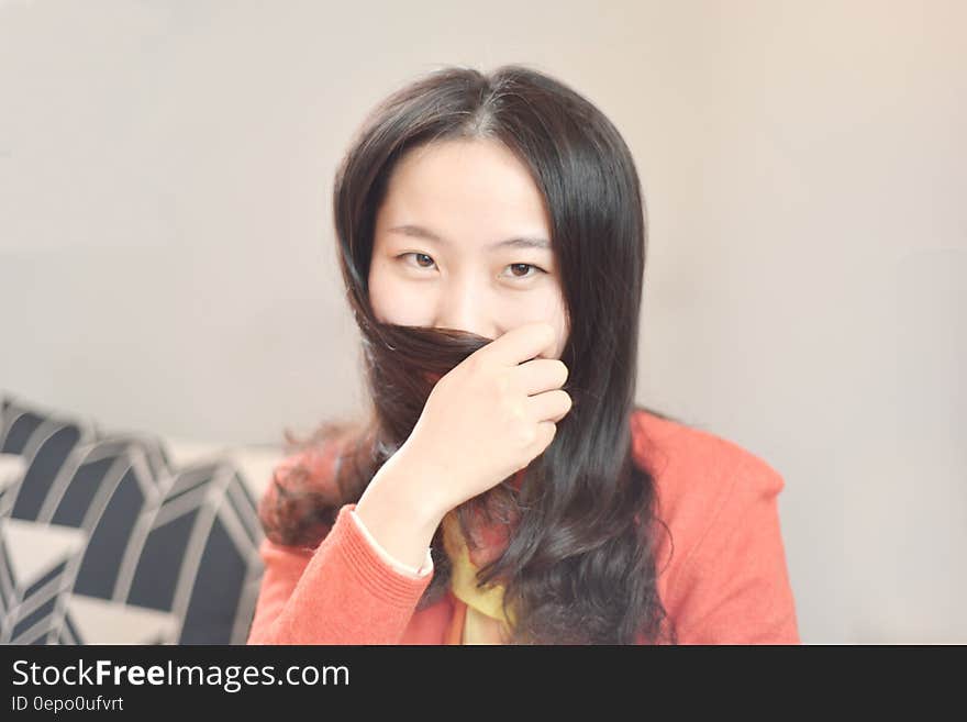 Woman Wearing Orange Blazer Sitting Beside Beige Wall