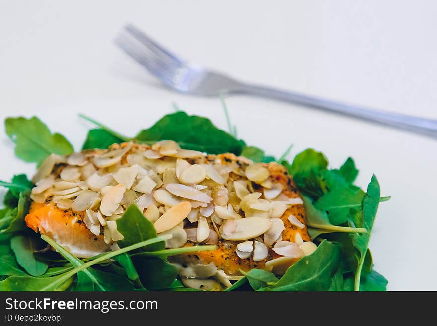 Green Leaf Covering Meat With Sesame Seeds With a Fork on the Side