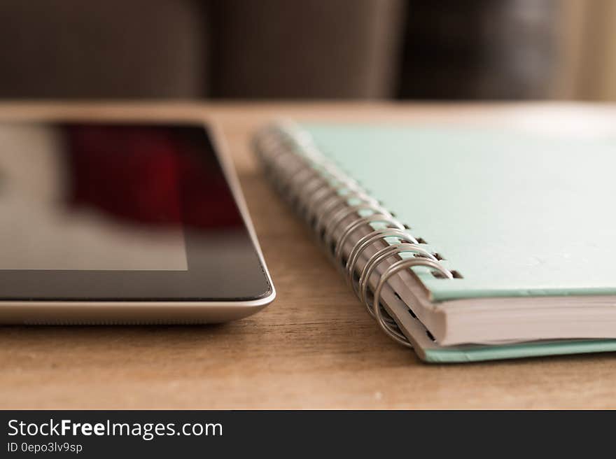 Close up of notebook and computer tablet on wooden desktop. Close up of notebook and computer tablet on wooden desktop.