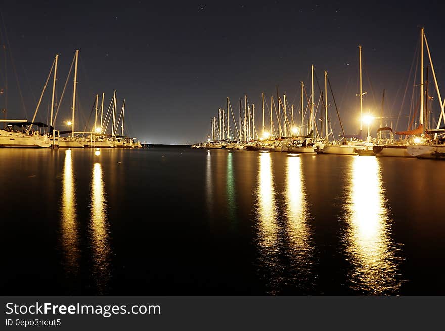 Sailboats illuminated in harbor at night.