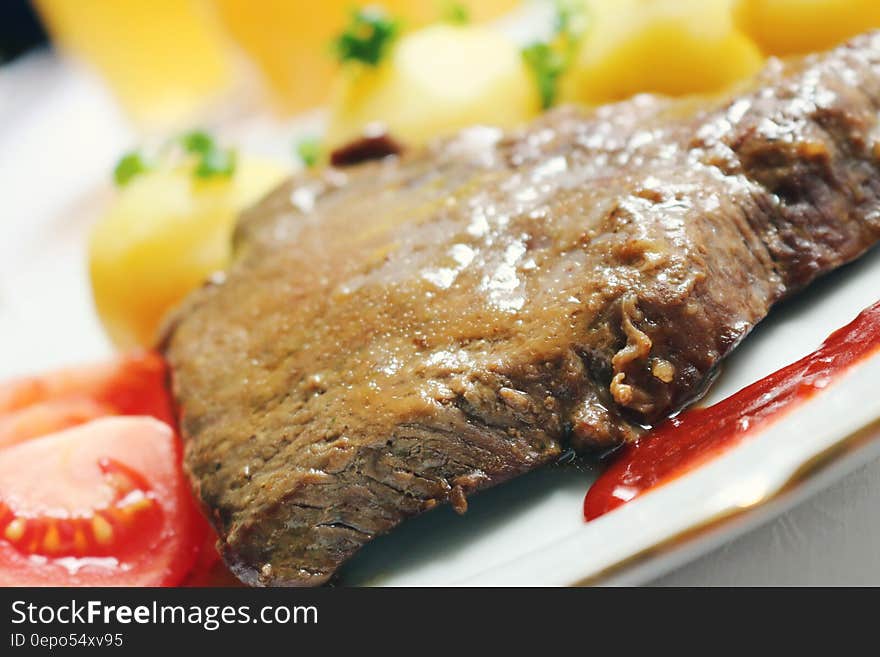 Close up of steak with tomatoes, sauce and roast potatoes on white china plate. Close up of steak with tomatoes, sauce and roast potatoes on white china plate.