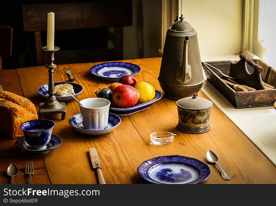 Blue and White Ceramic Plate Next to Apple Fruit and Brown Tea Pot