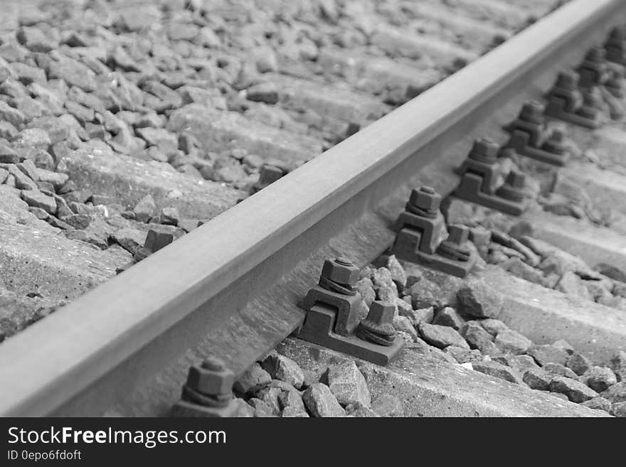 Black Metal Bolts in Silver Metal Train Rail Track Surrounder by Gray Stones