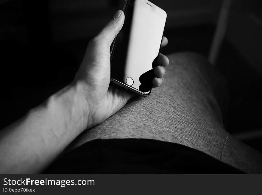 Close up of man's hand holding smartphone in black and white.