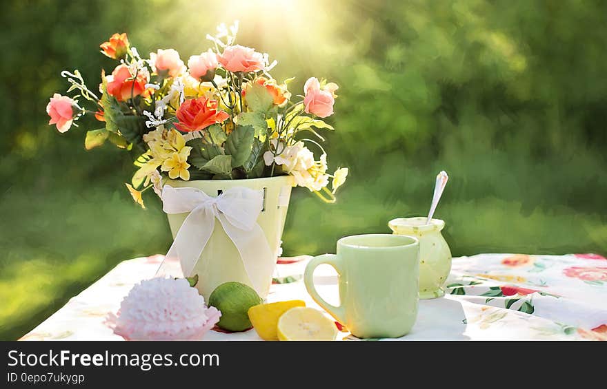 Assorted Flowers on Container Beside Mug on Table