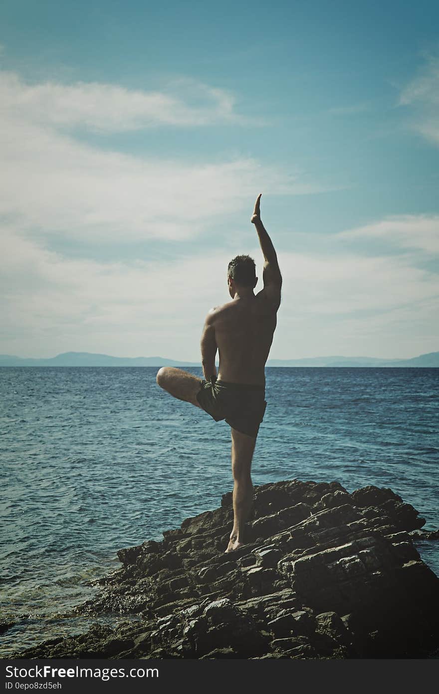 Topless Man Standing on Rock Formation Using Right Leg Only