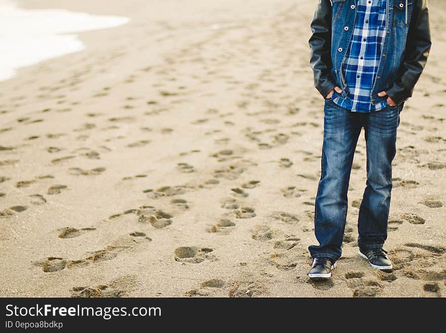 A casually dressed man standing on a sandy beach. A casually dressed man standing on a sandy beach.