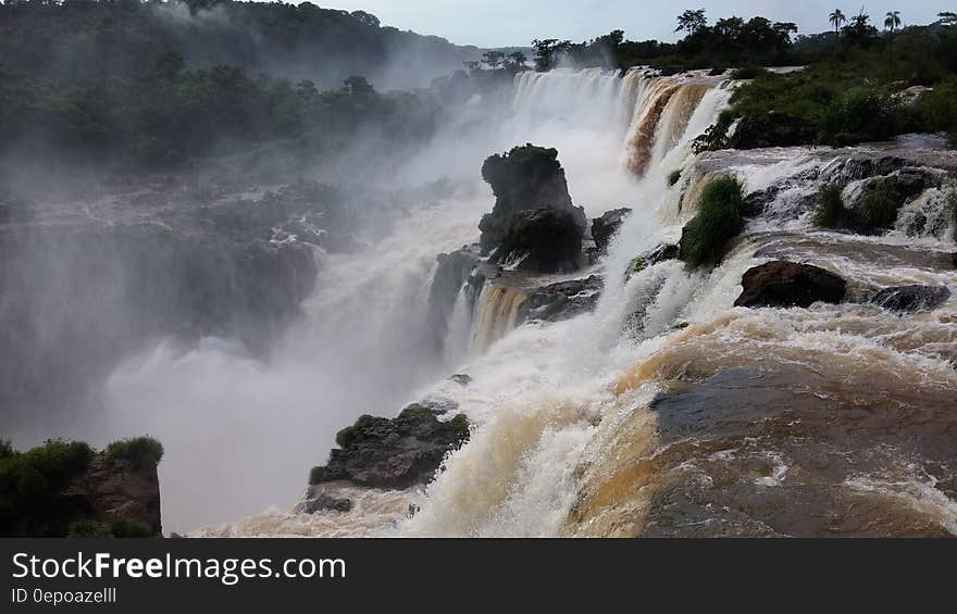 Water Falls Under White Clouds and Blue Sky during Daytime