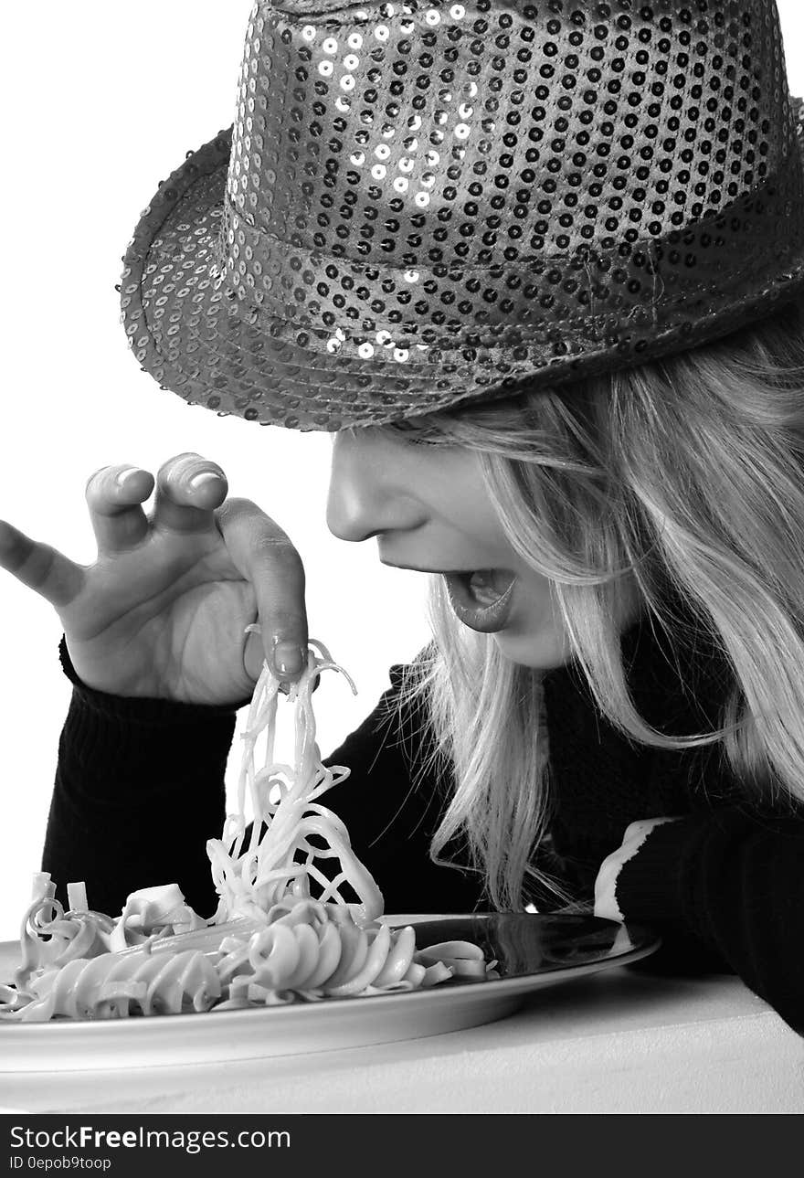 Woman in Sweater and Sequin Fedora Hat Holding Noodles in Grayscale Photography