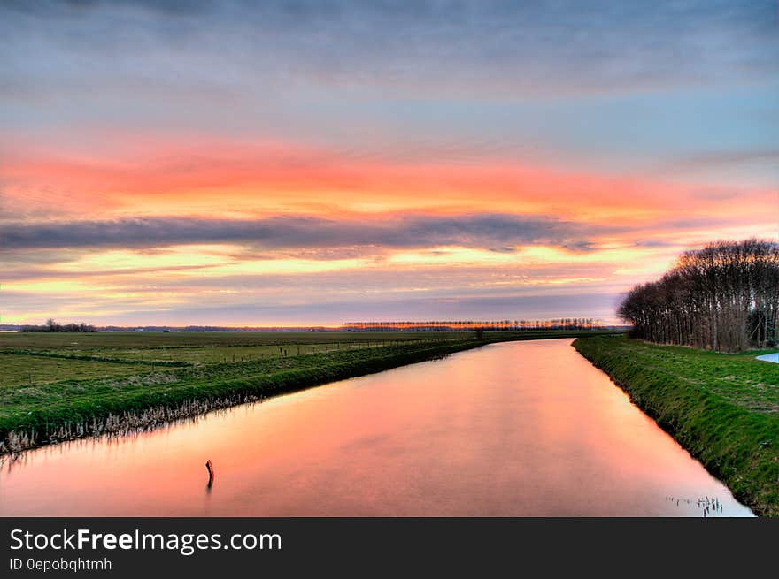 Sunset over green fields along river banks in countryside. Sunset over green fields along river banks in countryside.