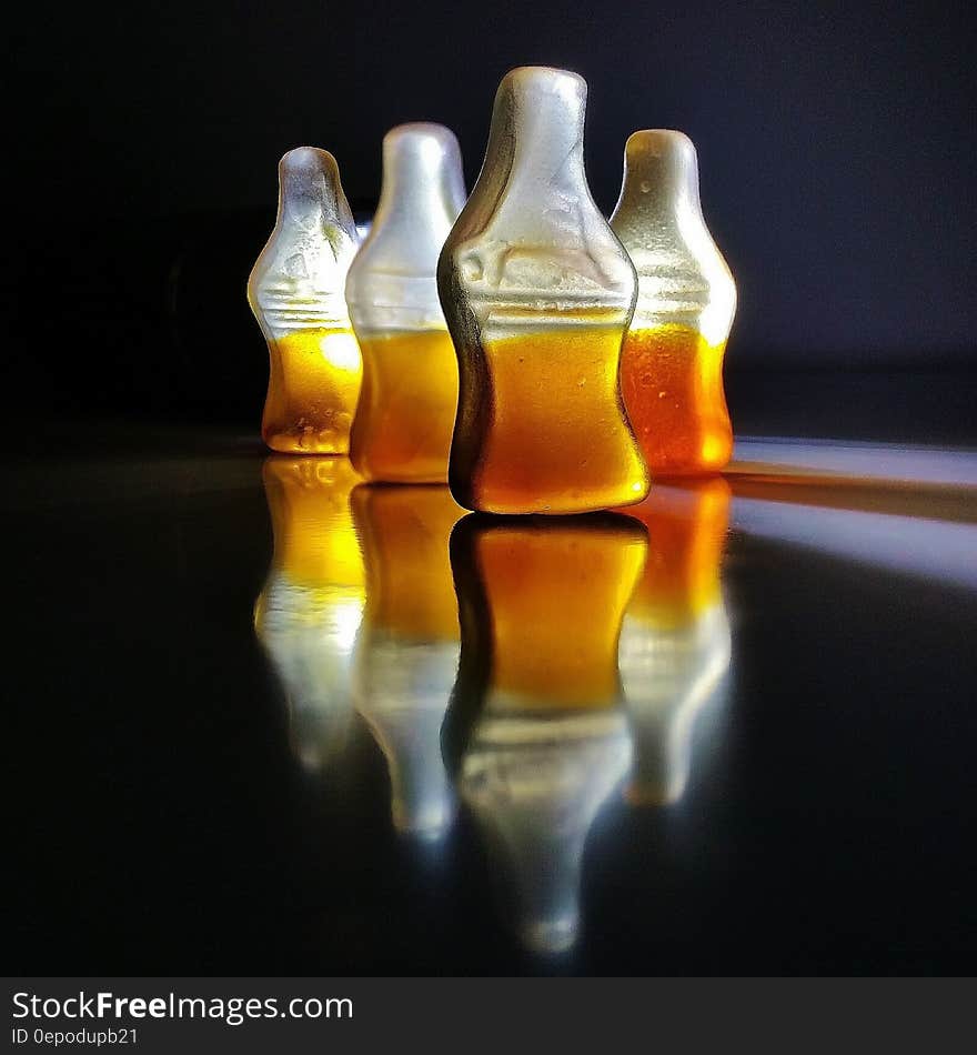 Close up of gummy cola candies reflecting on black.