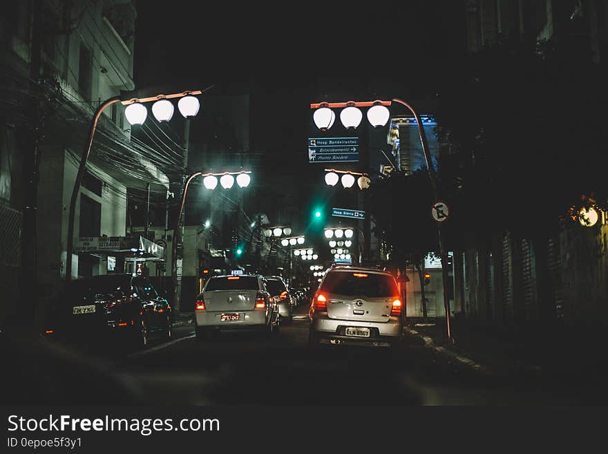 A view of a street at night with cars and streetlights hanging over. A view of a street at night with cars and streetlights hanging over.