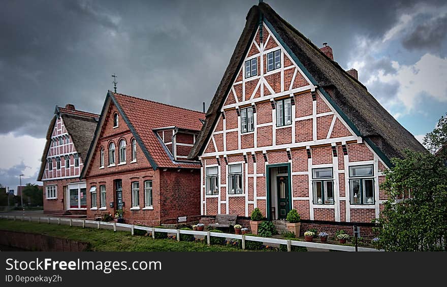 Brick homes with thatched rood on green lawns against cloudy skies. Brick homes with thatched rood on green lawns against cloudy skies.