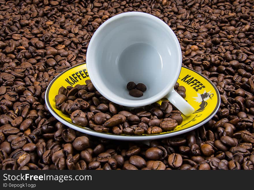 White Ceramic Cup on Yellow Plate With Coffee Beans