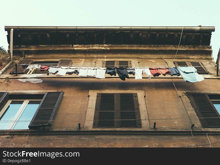 Hanging Clothes and Pants Beside Brown Building