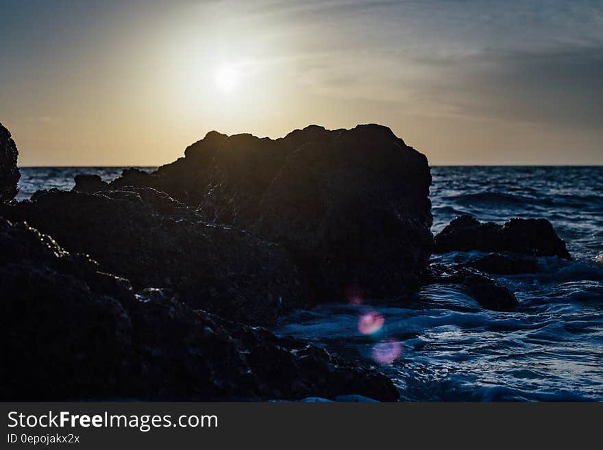 Black Stones on Sea Side during Sunset