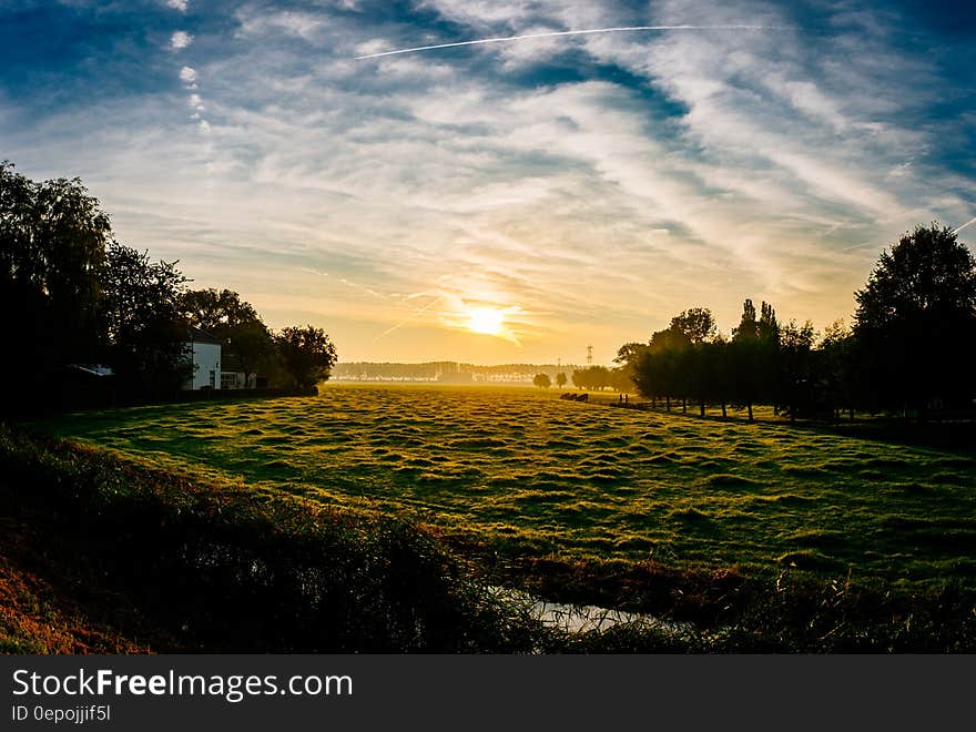 Sunset over rural green meadow lined with trees. Sunset over rural green meadow lined with trees.