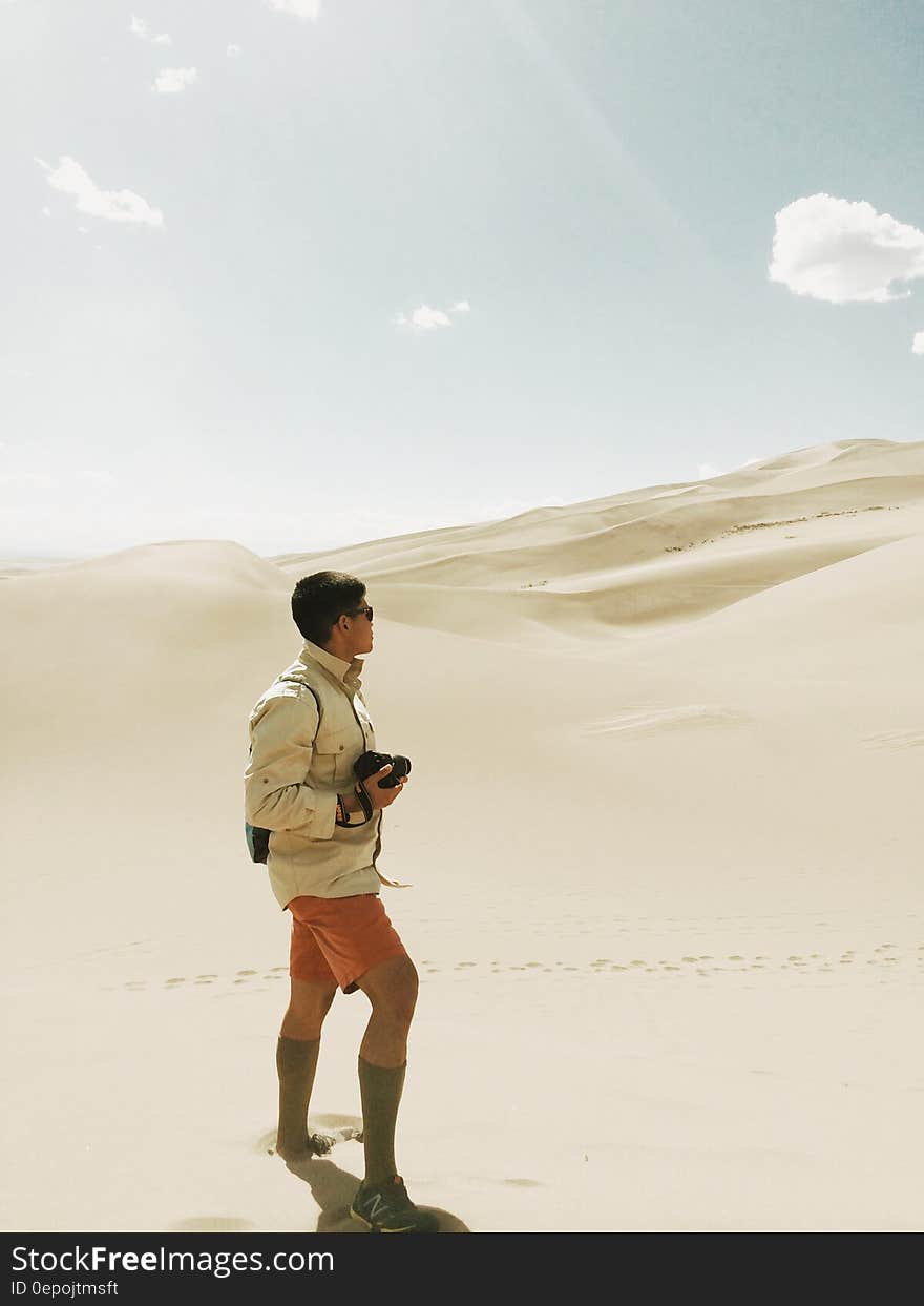 A photographer standing in a sandy African desert watching the dunes. A photographer standing in a sandy African desert watching the dunes.