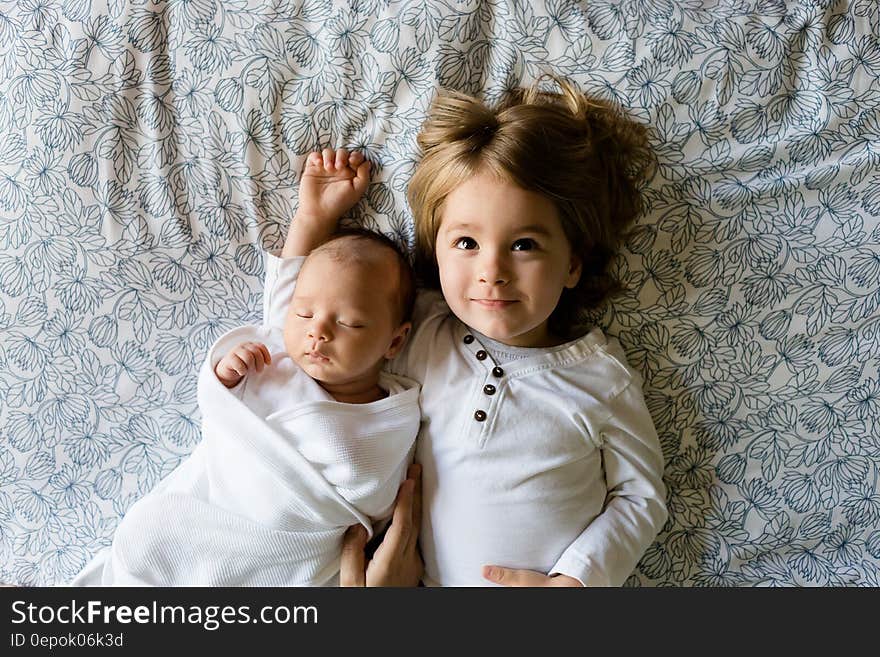 A young boy and his baby brother lying on a bed. A young boy and his baby brother lying on a bed.