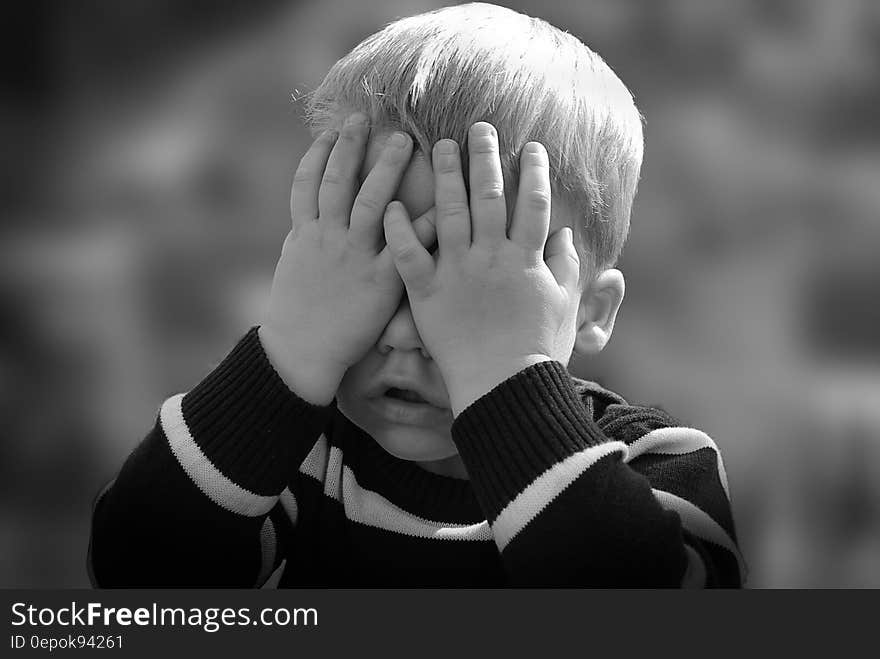 Boy in Black and White Sweater Covering His Face With His Tow Hand