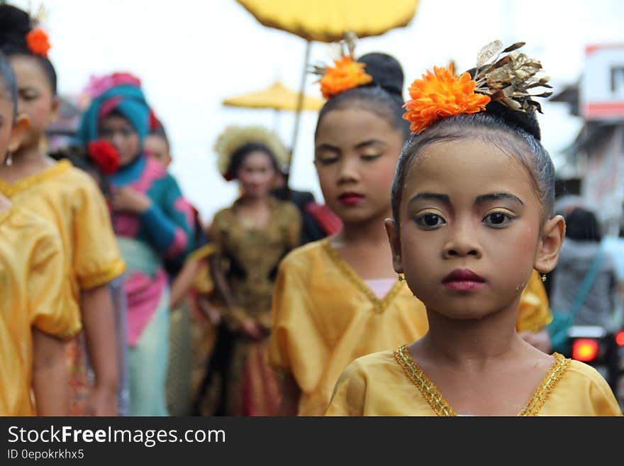 A group of Asian children,beautifully dressed, most in gold, with selective focus on one small charming young girl wearing flowers to decorate her hair. A group of Asian children,beautifully dressed, most in gold, with selective focus on one small charming young girl wearing flowers to decorate her hair.