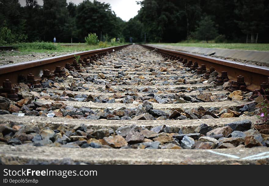 Close up of gravel between ties on railroad track through green field on sunny day. Close up of gravel between ties on railroad track through green field on sunny day.