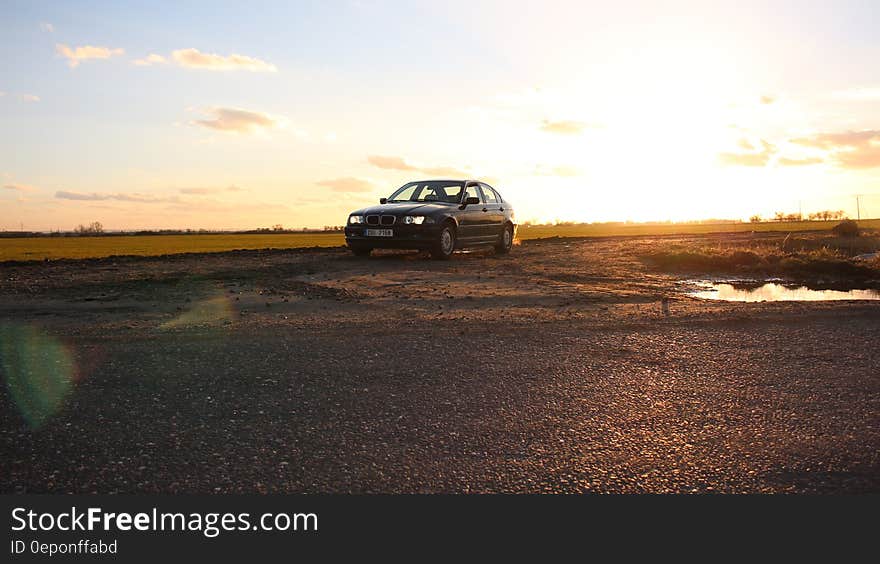 A car parked next to a field at sunset. A car parked next to a field at sunset.