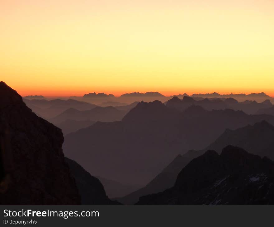 Silhouette of Hills Under Orange and Yellow Sky during Sunset