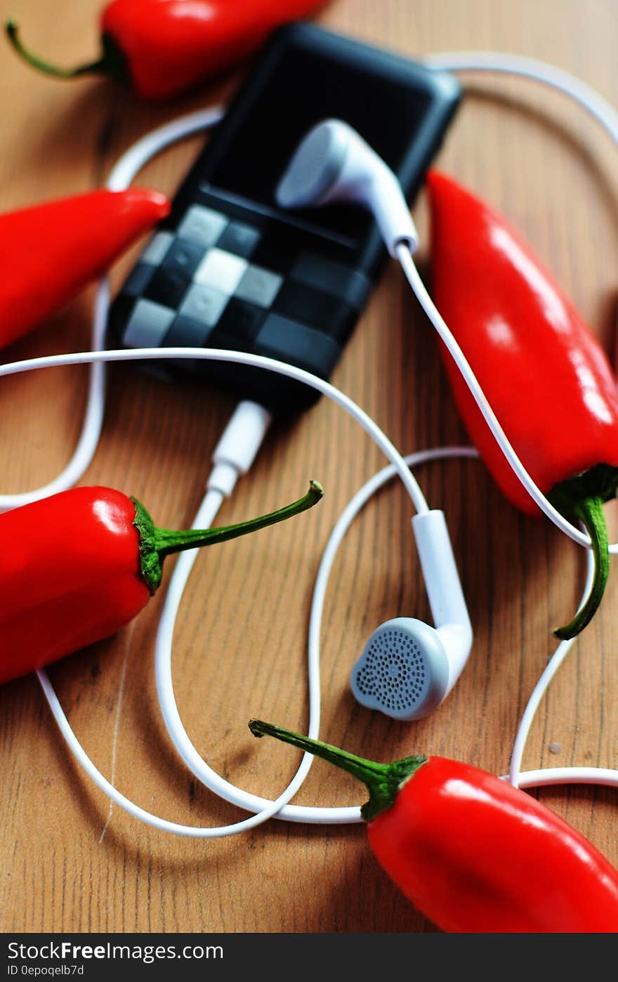 A portable music player with headphones and red chili peppers. A portable music player with headphones and red chili peppers.