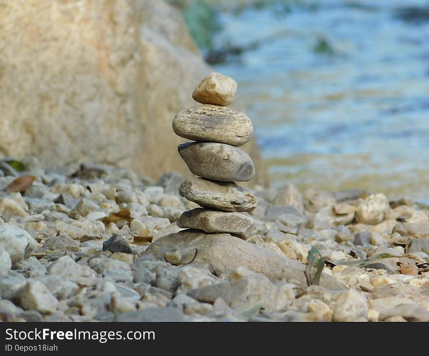 Closeup of an unstable pile of stones on a river bank or beside the sea with selective focus, blurred blue background. Closeup of an unstable pile of stones on a river bank or beside the sea with selective focus, blurred blue background.