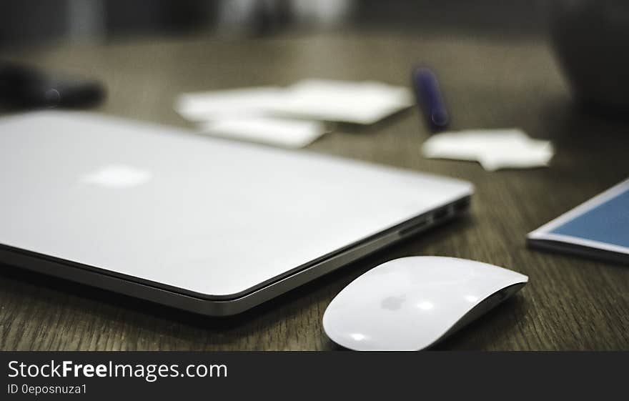 Apple macbook with bluetooth mouse on wooden desk. Apple macbook with bluetooth mouse on wooden desk.