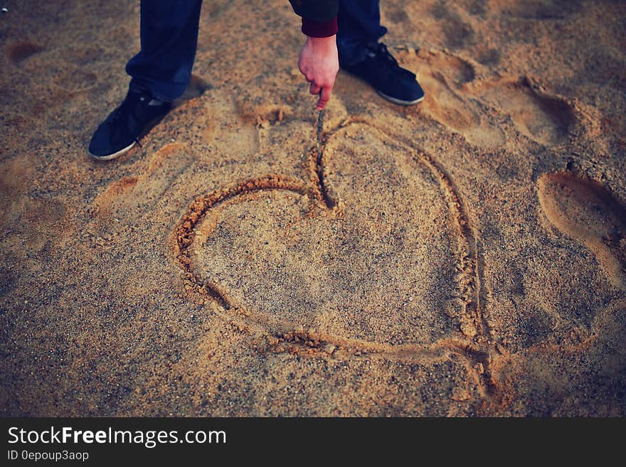 Hand drawing heart in the sand