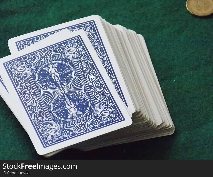 A deck of cards and a coin on green background.