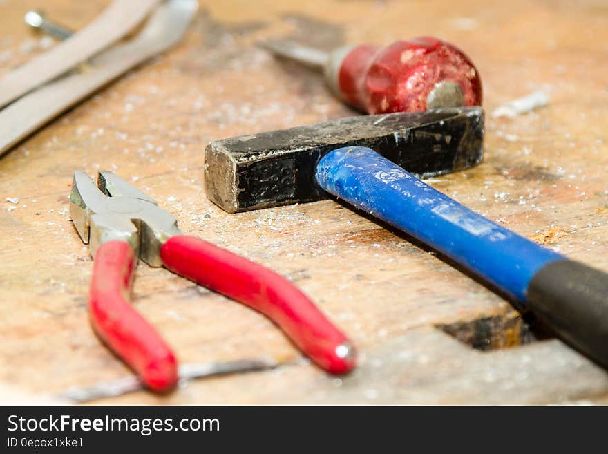 Red and Gray Pliers Beside Blue and Black Hammer