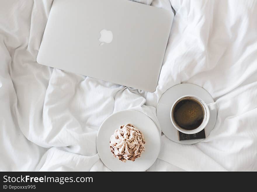 Laptop computer on bed linens with white china cup of coffee and breakfast. Laptop computer on bed linens with white china cup of coffee and breakfast.