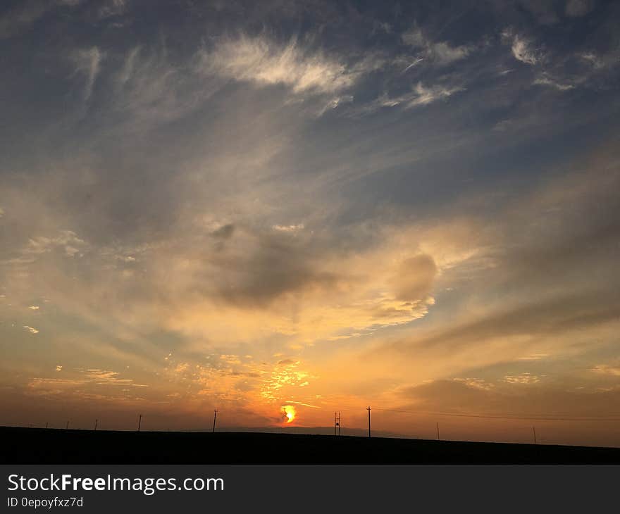 Sunset in skies over rural fields with electricity lines and poles. Sunset in skies over rural fields with electricity lines and poles.