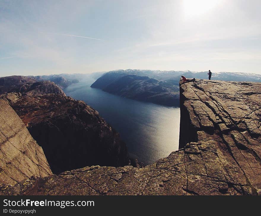 Person standing on edge of rocky precipice over river on sunny day. Person standing on edge of rocky precipice over river on sunny day.